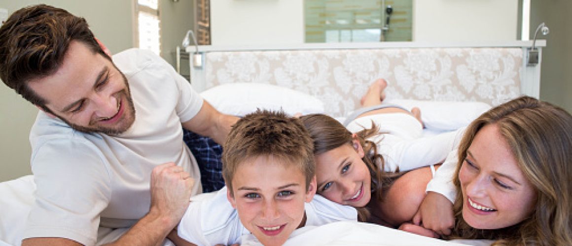 Happy family playing on the bed at home in bedroom